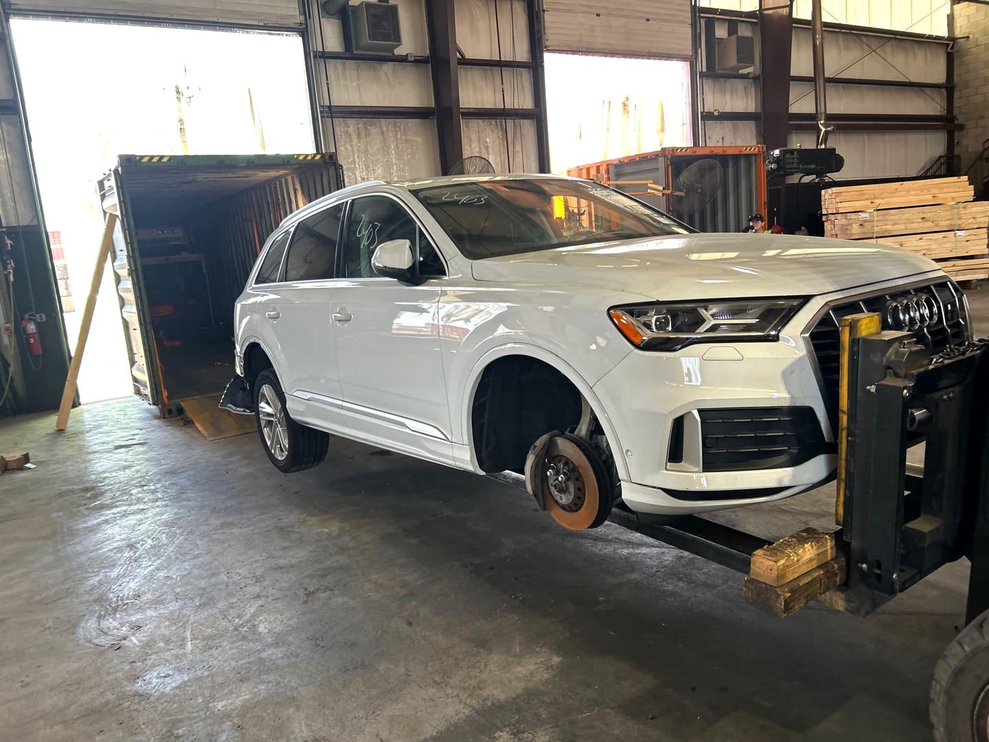 Audi Q7 blanc soulevé par un chariot élévateur pour le chargement en conteneur